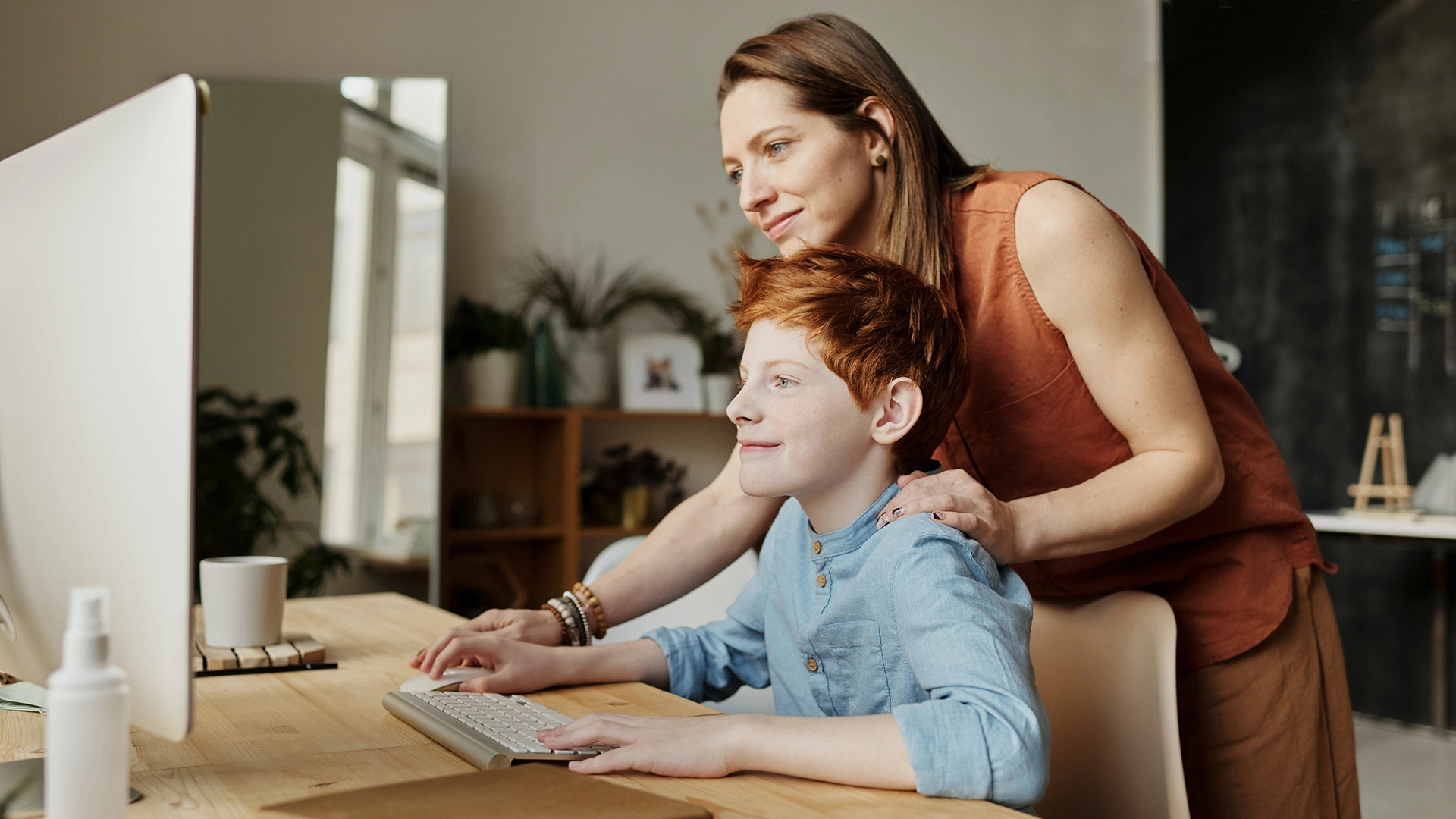 Une lère aide son fils à faire ses devoirs sur ordinateur